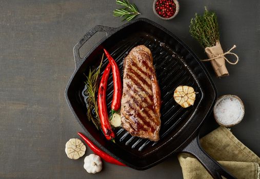 Keto ketogenic diet beef steak, well done fried striploin on grill pan. Paleo food recipe with grilled meat, butter and seasoning. Close up, top view, copy space