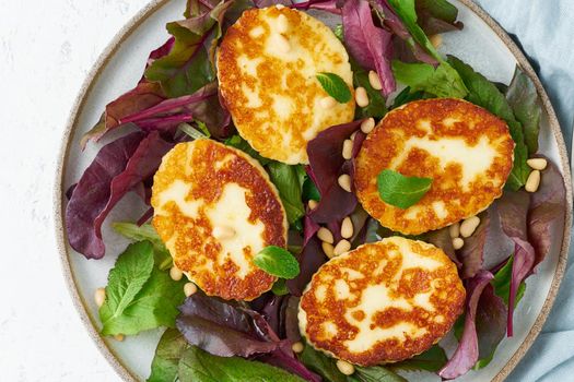 Cyprus fried halloumi with salad mix, beet tops. Lchf, pegan, fodmap, paleo, scd, keto, ketogenic diet. Balanced food, clean eating recipe. Top view, a white background, close up