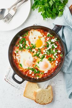 Shakshouka, eggs poached in sauce of tomatoes, olive oil, peppers, onion and garlic, Mediterranean cousine. Keto meal, FODMAP recipe, low carb. Top view, vertical