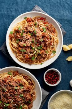 Pasta Bolognese Linguine with mincemeat and tomatoes, parmesan cheese. Italian dinner for two, dark blue tablecloth. Top view, close up