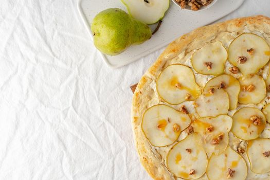 Part of Fruit sweet homemade pear pizza with cheese and honey, Rustic Italian savory food with pastry dough, top view, copy space