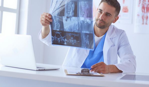 Handsome doctor is talking with young female patient and making notes while sitting in his office
