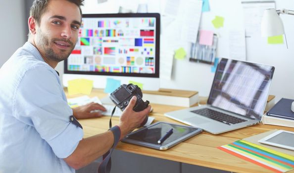 Portrait of young designer sitting at graphic studio in front of laptop and computer while working online