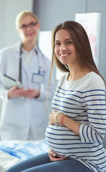 Beautiful smiling pregnant woman with the doctor at hospital.