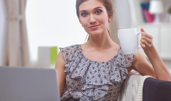 Smiling woman with documents sitting on the desk with laptop