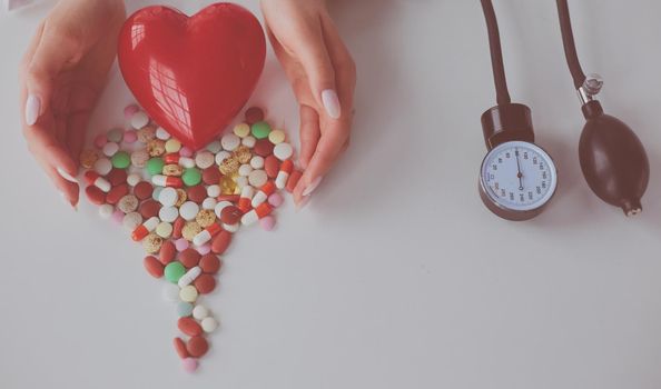 Cardiologist with red heart and stethoscope at table.