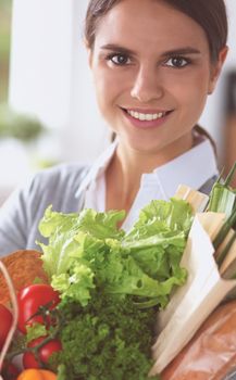 Young woman holding grocery shopping bag with vegetables.