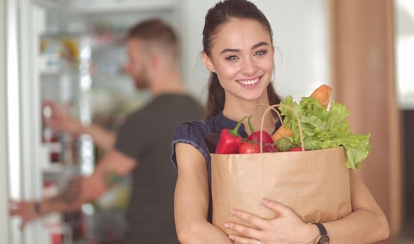 Young couple in the kitchen , woman with a bag of groceries shopping.