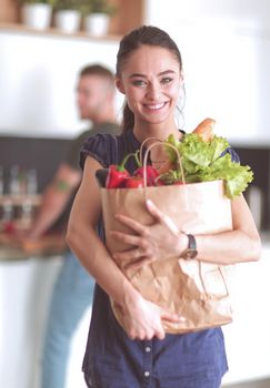 Young couple in the kitchen , woman with a bag of groceries shopping.