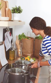 Beautiful woman standing in kitchen with apron, standing