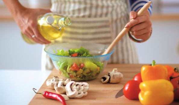 Young woman mixing fresh salad .