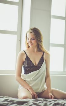 Portrait of beautiful young woman in nightwear on bed.