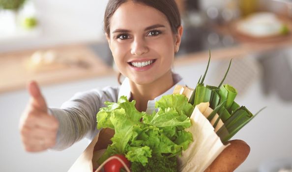 Young woman holding grocery shopping bag with vegetables