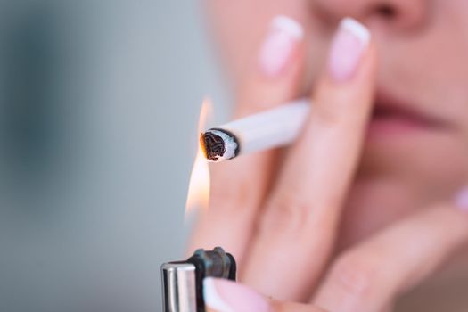 Closeup of young woman lighting cigarette with lighter. Smoking addiction and bad habit concept. High quality photo