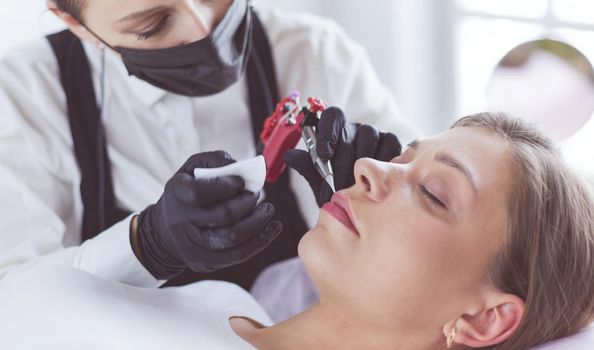 Cosmetologist applying permanent make up on eyebrows.