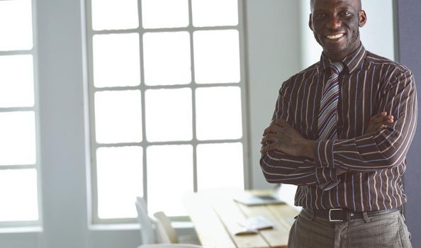 Portrait of an handsome black businessman standing in office.