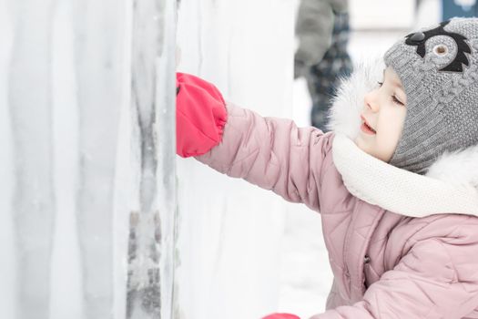 little cute girl explores the ice fortress in winter.