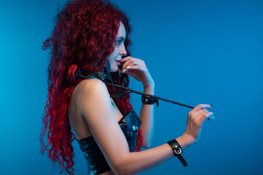 the portrait of a girl with a chic hairstyle and red hair with a leather rose in her hands