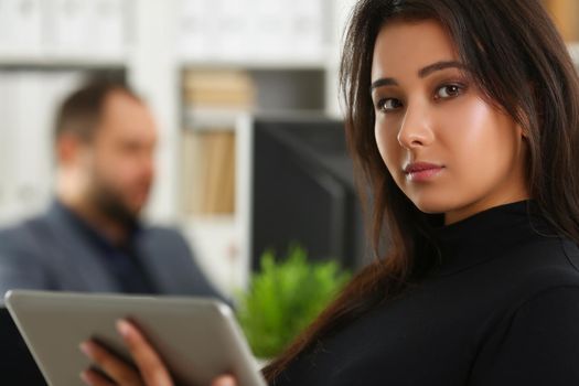 Portrait of lovely brunette woman sit with digital tablet device. Pretty secretary in black outfit work in big corporation. Business, office life concept