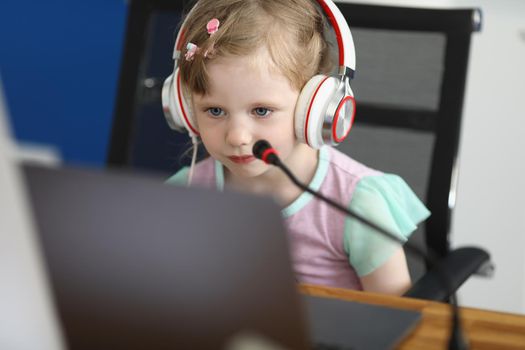 Portrait of little cute child watch cartoon on laptop or studying online, kid wear headset with microphone. Childhood, development, preschool class concept