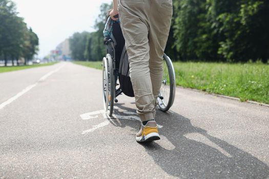 Low angle of man drive person in wheelchair, friend visit someone in nursing house. Go for walk in park, treatment for recovery. Disability, health concept