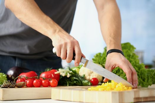 Close-up of professional chef cut yellow pepper with sharp knife on cutting board on kitchen. Person cook new recipe. Cooking, food, dish, homemade concept