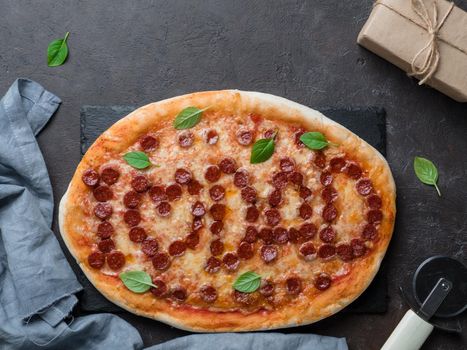 Father's day background. Pepperoni pizza with i love dad lettering and gift box on black table. Father day concept, recipe and idea. Top view or flat-lay. Copy space for text.