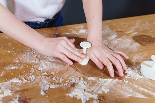 A little girl makes heart-shaped cookies from rye dough. The concept of Valentine's Day and healthy baking. Cooking cookies in close-up.