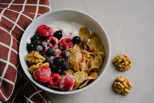 Delicious and healthy breakfast. Natural yogurt, cereals and berries. Hearty breakfast with frozen blackcurrant berries and raspberries. Multi-lacquered cereals for breakfast. Walnuts.