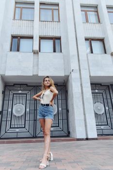 Stylish vertical urban portrait of a young woman against the backdrop of a tall building. Woman Teenager Portrait Hipster Style Concept.