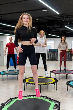Women's and men's group on a sports trampoline, fitness training, healthy life - a concept trampoline batut workout health, from fit athletic in sporty for sport body, wellness beautiful. Legs beauty loss, coach