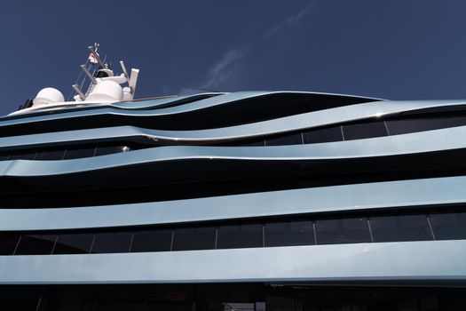 Bottom view of decks of huge yacht of blue color at sunny day, glossy board of the motor boat, sun reflection on glossy board, blue sky is on background. High quality photo