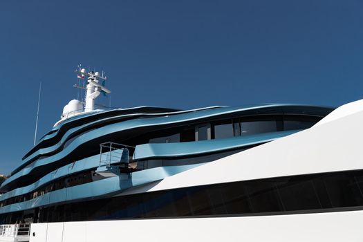 Bottom view of decks of huge yacht of blue color at sunny day, glossy board of the motor boat, sun reflection on glossy board, blue sky is on background. High quality photo