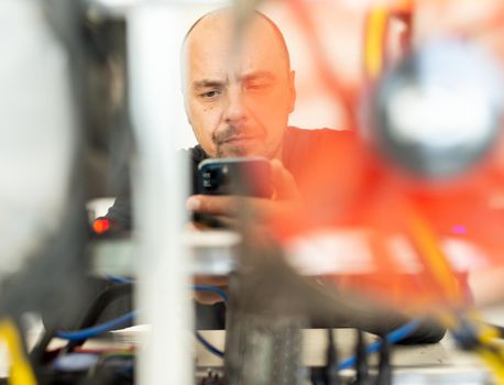 Young programmer adjusting cryptocurrency mining rig to optimal operational settings. High quality photo