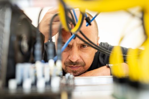 Young programmer adjusting cryptocurrency mining rig to optimal operational settings. High quality photo