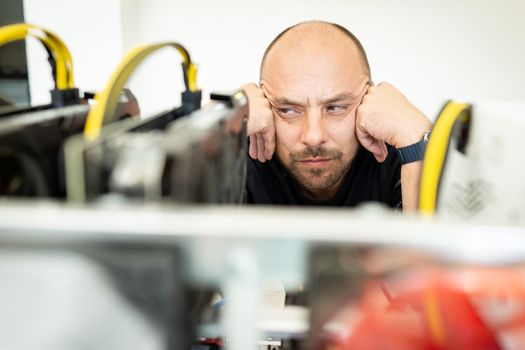 Young programmer adjusting cryptocurrency mining rig to optimal operational settings. High quality photo