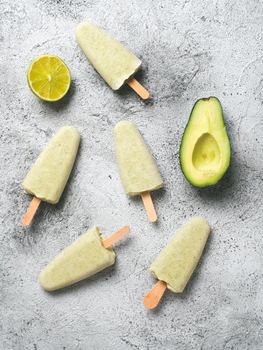 Homemade raw vegan avocado lime popsicle. Sugar-free, non-dairy green ice cream on gray background. Copy space. Top view. Ideas and recipes for healthy snack, dessert or smoothie. Vertical.