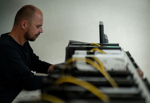 Young programmer adjusting cryptocurrency mining rig to optimal operational settings. High quality photo