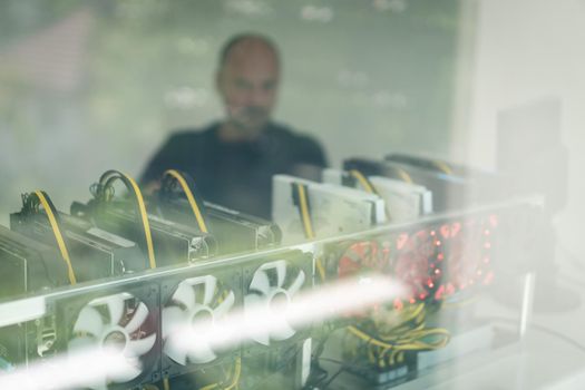 Young programmer adjusting cryptocurrency mining rig to optimal operational settings. High quality photo