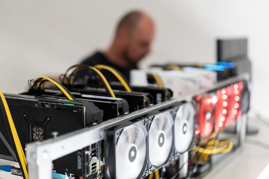 Young programmer adjusting cryptocurrency mining rig to optimal operational settings. High quality photo