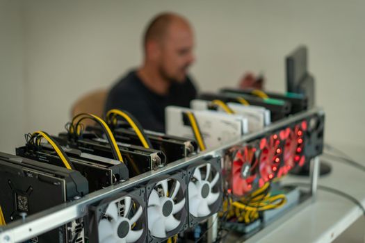 Young programmer adjusting cryptocurrency mining rig to optimal operational settings. High quality photo