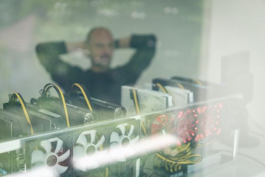 Young programmer adjusting cryptocurrency mining rig to optimal operational settings. High quality photo