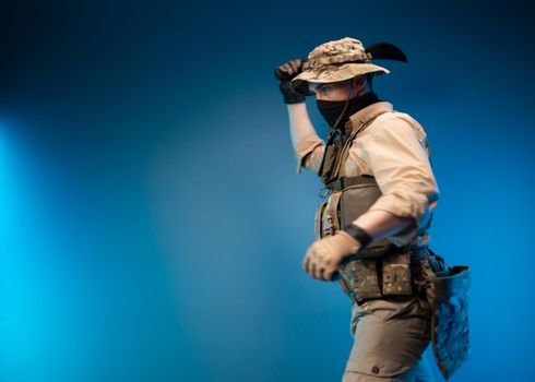 an army soldier in military clothes swings to strike with a machete in his hand