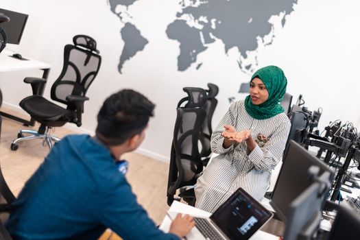 Multiethnic startup business team Arabian woman wearing a hijab on meeting in modern open plan office interior brainstorming, working on laptop and desktop computer. Selective focus. High-quality photo