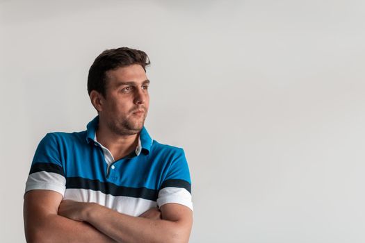 Formal business male portrait. A confident successful casual businessman or manager stands in front of a white background, arms crossed, looking directly at the camera and smiling friendly. High-quality photography.