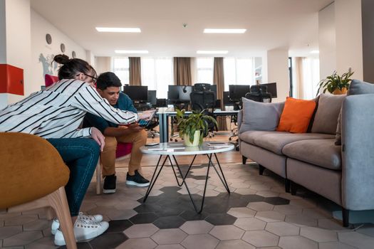 Group of casual multiethnic businesspeople taking a break from the work doing different things while enjoying free time in relaxation area at modern open plan startup office. High-quality photo