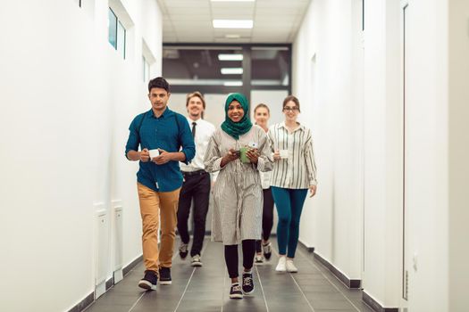 Multi-ethnic startup business team walking through the hallway of the building while coming back from a coffee break. High-quality photo
