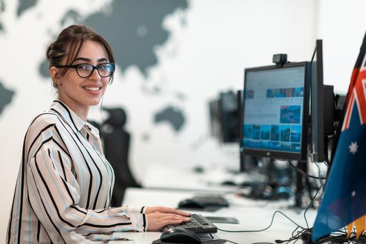 Casual businesswoman working on a desktop computer in modern open plan startup office interior. Selective focus. High-quality photo