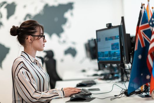 Casual businesswoman working on a desktop computer in modern open plan startup office interior. Selective focus. High-quality photo