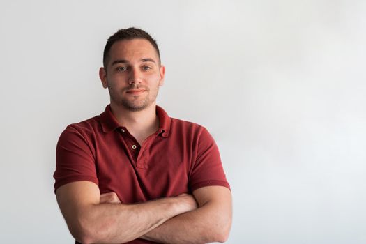 Formal business male portrait. A confident successful casual businessman or manager stands in front of a white background, arms crossed, looking directly at the camera and smiling friendly. High-quality photography.